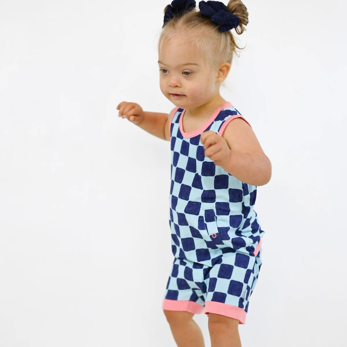 Girl wears checkers romper in blue with pink trim